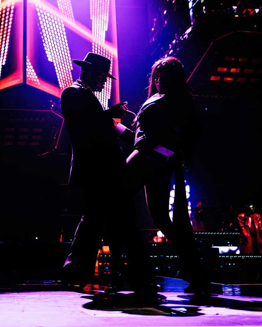 Ne-Yo and a dancer face to face in near-silhouette, lit magenta by the LED panels behind them